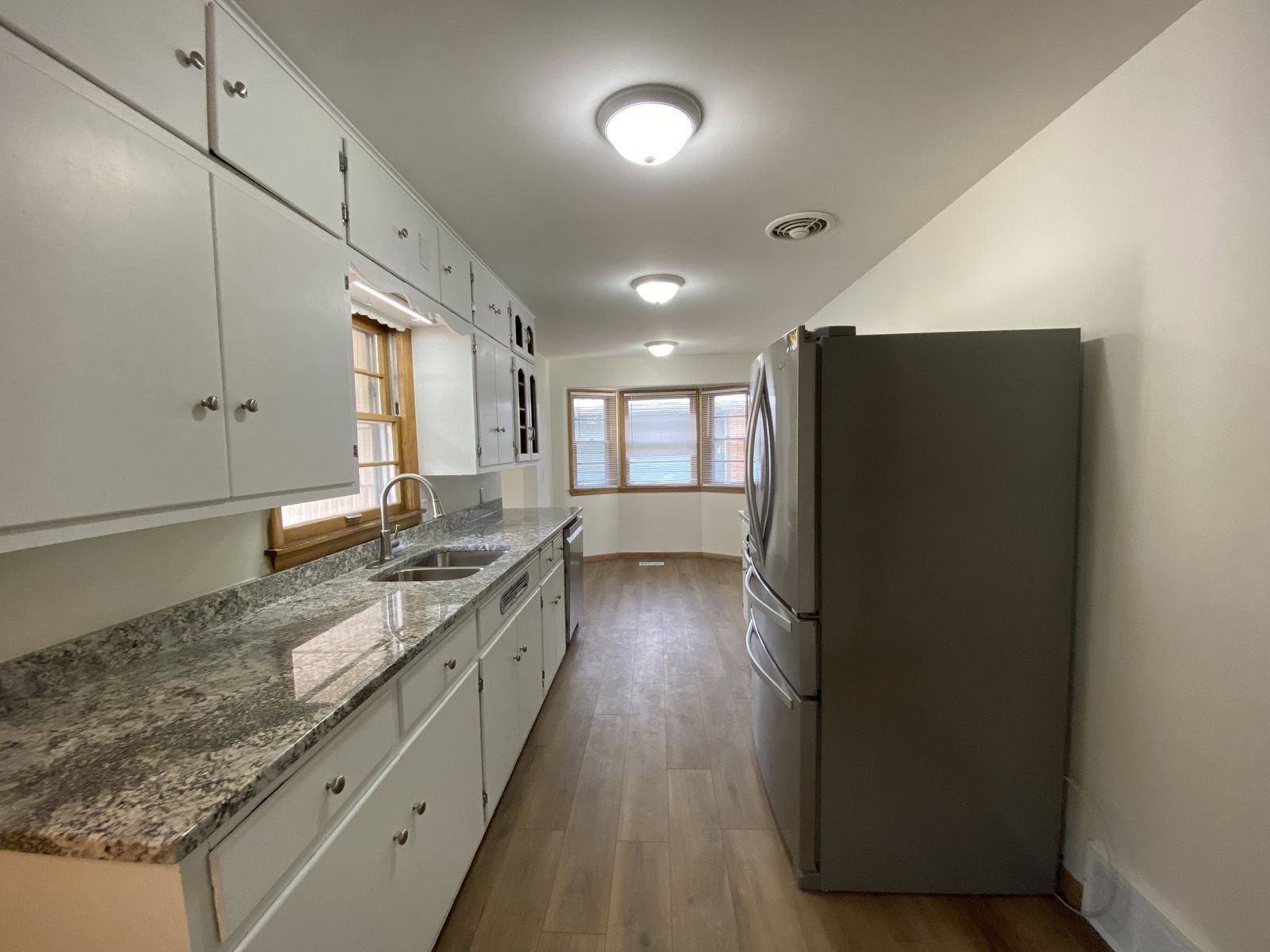 Renovated kitchen with white cabinets, granite counters and stainless appliances
