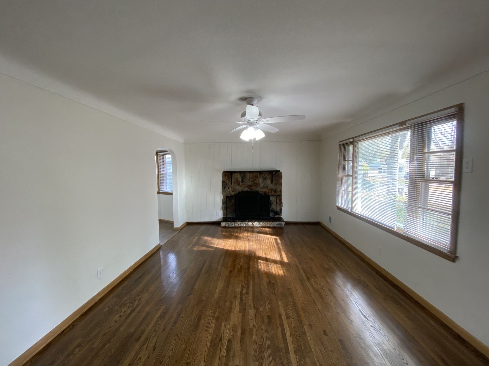 Renovated living room with refinished wood floors and a stone fireplace